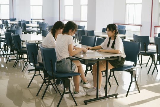 三个漂亮的亚泰学生在学校内的女宿舍开会。一起做作业。