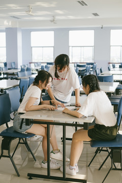 三个漂亮的亚泰学生在学校内的女宿舍开会。一起做作业。