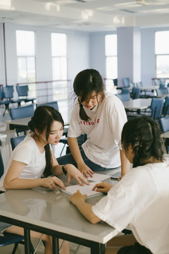 三个漂亮的亚泰学生在学校内的女宿舍开会。一起做作业。