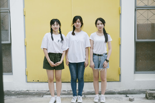 街上穿着白衬衫的三位美丽的亚泰女青年。时尚肖像。