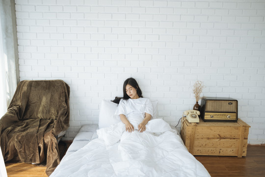 可爱的亚洲女士独自睡在老式白色房间的床上。