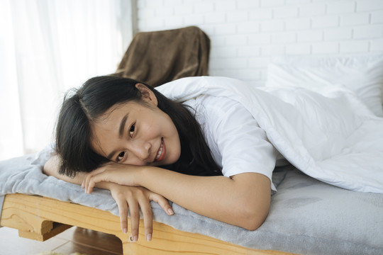在卧室里，可爱的亚洲女人把头靠在胳膊上，快乐的女孩，熟睡的概念。