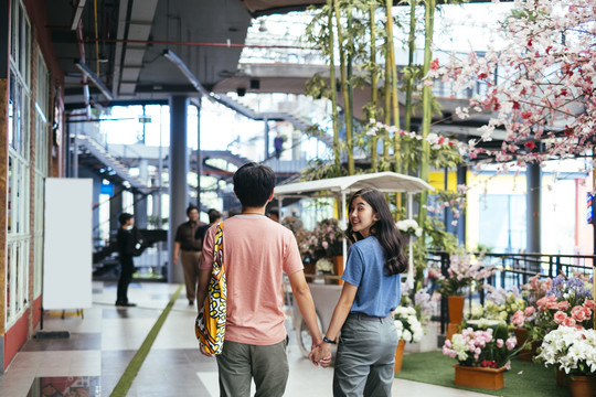一对亚泰夫妇手牵手走在购物中心。