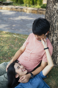 亚泰夫妇在树下休息，用耳机听音乐，在公园野餐。