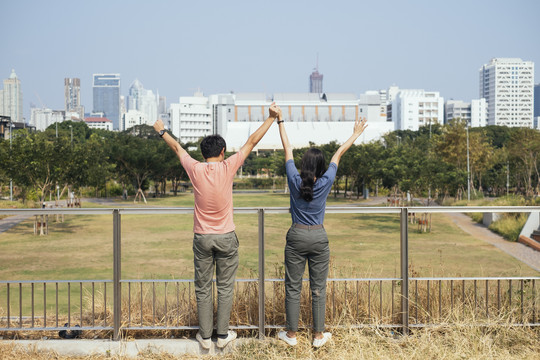 后视图-亚泰夫妇手牵手在公园自由的姿态。