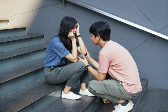 亚泰夫妇有问题和争吵。一个男人正试图和坐在楼梯上的女孩说话。爱情问题。