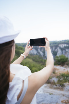 美丽的亚泰女游客用智能手机拍风景照。