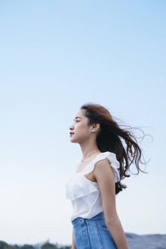 美丽的泰国亚裔旅行家妇女在大自然中迎风的肖像。侧视图。野外的性感女孩。