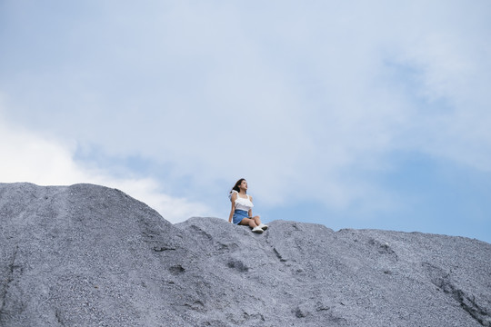 美丽的亚泰旅行家女子坐在山顶上。