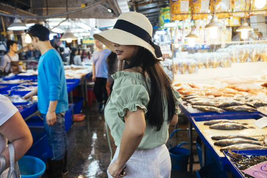 美丽的棕褐色亚洲旅游妇女在泰国当地市场寻找海鲜。