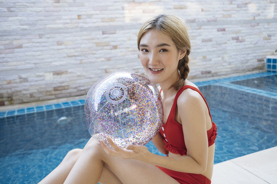 身着红色比基尼的泰国美女在游泳池附近玩透明闪光球。