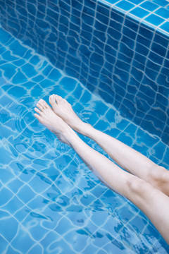 美女的腿在游泳池里泼水。