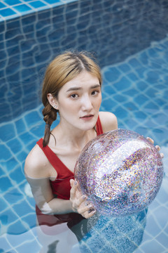 身着红色比基尼的泰国美女在游泳池里游泳，透明闪闪发光。