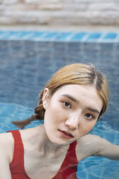 在游泳池里，一个穿着红色比基尼的泰国性感美女的肖像画。