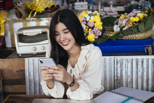 快乐美丽的泰国职业女商人穿着休闲衬衫和朋友聊天。快乐的表情。科技让我们更亲近。