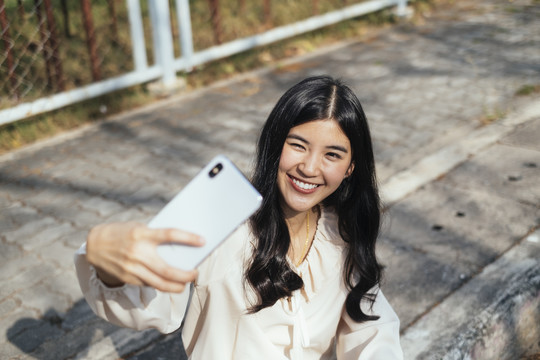 开朗微笑的女人用智能手机自拍。虚拟博客。写博客。