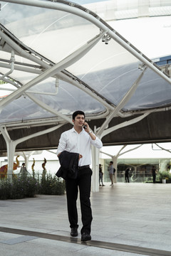穿着白色正式衬衫的成熟亚洲商人在天桥上打电话。