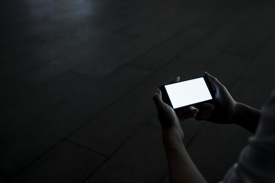这是一张智能手机的剪贴图片，当男子在夜间使用它进行游戏和社交媒体时，屏幕上亮着灯。