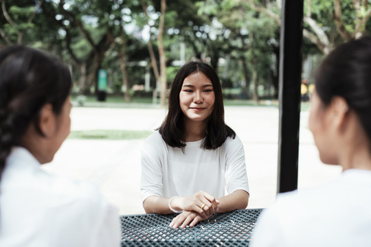 三对双胞胎姐妹一起坐在操场旁公园的金属桌旁。