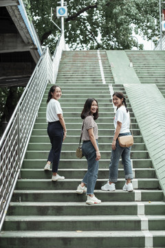 三对双胞胎姐妹一起走上公园的绿色楼梯。