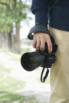 当男摄影师拿着数码相机的照片在他身后的复印空间。