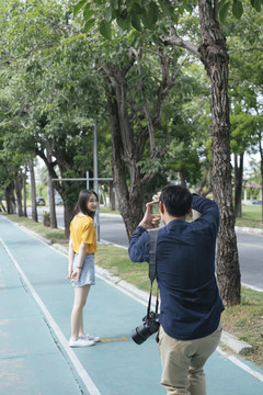 男摄影师在给一个女孩在自行车道上拍照前用手定格。