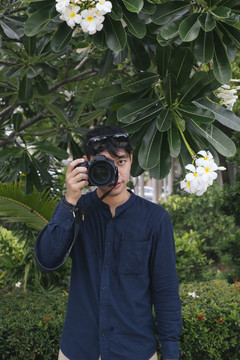 雄性摄像机在鸡蛋花树下拍摄。