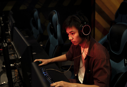 泰国专业玩家在红色霓虹灯下玩电脑游戏。愤怒的头脑发热的玩家。
