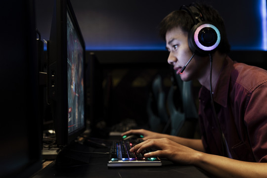 在电脑上玩游戏的年轻亚洲玩家，有着严肃的感觉。
