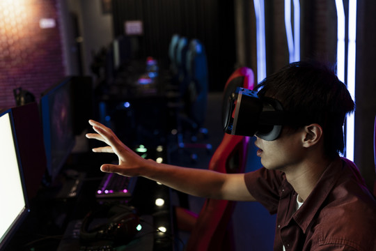 在网吧里戴着虚拟现实眼镜的亚洲少年。VR耳机。