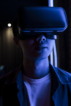 戴着虚拟现实眼镜的年轻人。亚洲青少年在蓝色霓虹灯下使用虚拟现实。