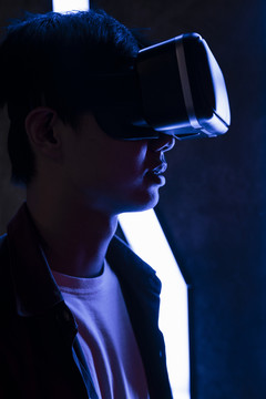 戴着虚拟现实眼镜的年轻人。亚洲青少年在蓝色霓虹灯下使用虚拟现实。