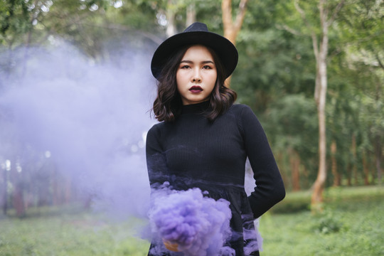 一个懒洋洋的女人，穿着哥特式的衣服，手里拿着紫色的烟火。