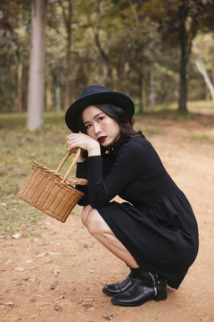 黑巫婆坐在森林里的路上，手里拿着药草篮。