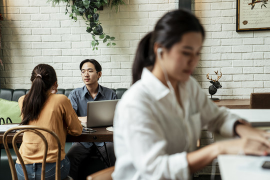 两个商务人士在后面接受采访。迷离的女人在前面，用白色耳机听音乐。