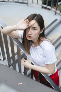 时尚写真-穿着白衬衫和红色运动裤的美丽亚洲年轻女子在过道上摆姿势。