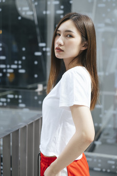 时尚写真-美丽的亚洲年轻女子在白色衬衫和红色运动裤在美丽的现代城市镜子背景。