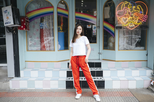 时尚写真-身穿白色衬衫和红色运动裤的泰国亚裔年轻女子站在街上。