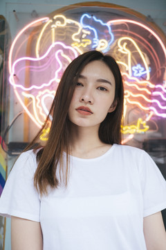 时尚写真-特写年轻的亚泰女性在霓虹灯背景下穿着白色衬衫。