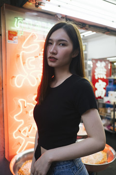 特写时尚肖像-美丽的时髦亚洲年轻女子在霓虹灯背景黑色衬衫。