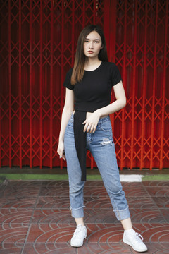 全长时尚肖像-美丽的时髦亚洲年轻女子在黑色衬衫和牛仔裤裤子红色穿梭门。