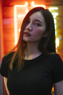 时尚写真-美丽的时髦亚洲年轻女子在霓虹灯背景黑色衬衫。夜间肖像。