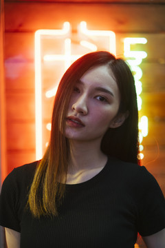 时尚写真-美丽的时髦亚洲年轻女子在霓虹灯背景黑色衬衫。夜间肖像。