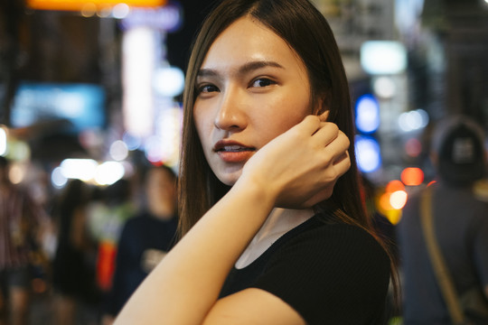 特写时尚写真-美丽的时髦亚洲年轻女子在黑色衬衫和牛仔裤裤子在曼谷市晚上。