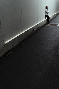 悲伤的商人靠墙站在阴暗的街巷里。