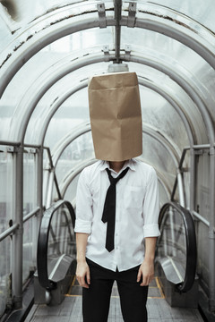 头上顶着硬纸袋的商人。在城市隧道里，商人用纸袋蒙头。