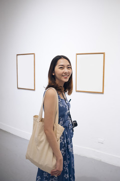 身着蓝色连衣裙的泰国亚裔年轻女子在美术馆欣赏风景。