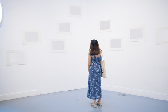 在白色美术馆，一位身着蓝色礼服的泰国亚裔年轻女子。