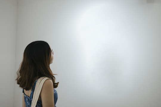 一个女人在美术馆里看着白色的空镜框。