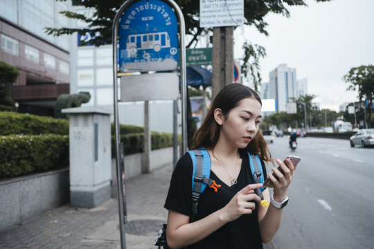 美丽的亚洲年轻女子背包客在曼谷市中心旅游。使用智能手机跟踪GPS应用程序的女性。